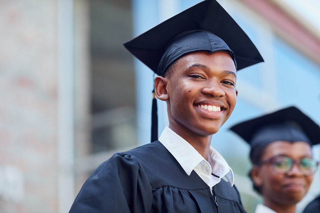 Our Vision - Portrait of a happy male student standing outside on his graduation day. Connections to the Future