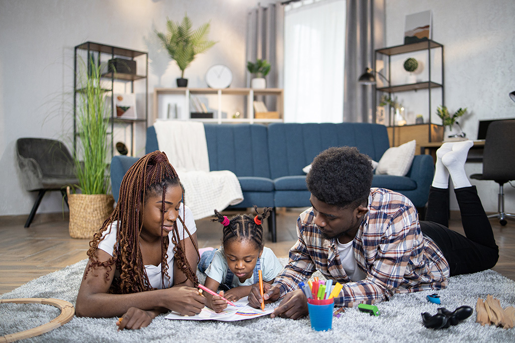 parents drawing with daughter while lying on the floor